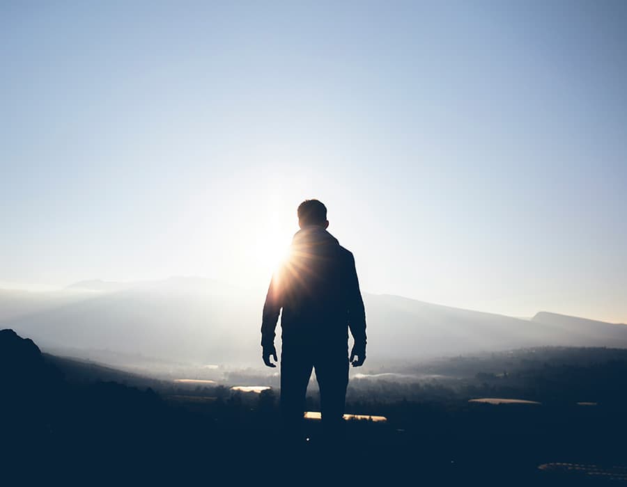 Standing before the sunrise over misted hills